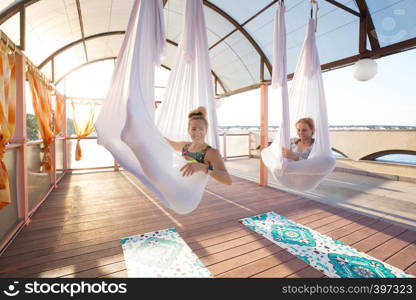 Healthy and fly Yoga Concept. happy smiling girls are sitting in hammocks in a fly yoga class