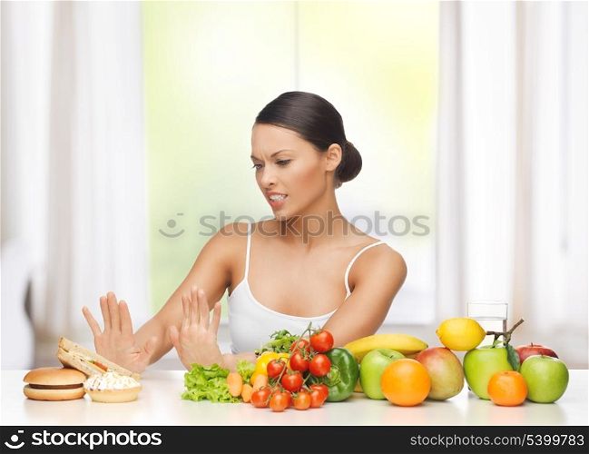 healthy and junk food concept - woman with fruits rejecting hamburger and cake