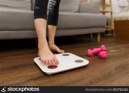 Healthy and weight loss concept, Young Asian woman stepping on weighing scales after weight control.