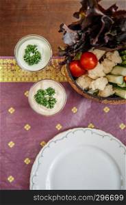 Healthy appetizer fresh vegetables dip, cauliflower, tomatoes, cabbage, cucumber with creamy ranch dressing sauce, top view shot