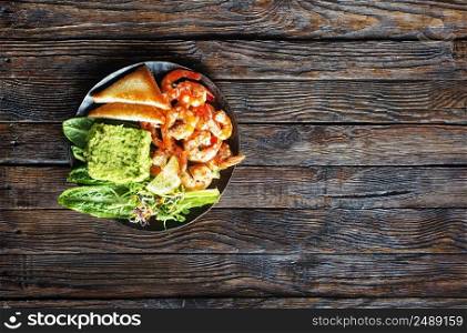 Healthy appetizer or snack avocado shrimp bruschetta. Fried shrimp and mashed avocado on black plate. Healthy appetizer or snack avocado shrimp bruschetta. Fried shrimp and mashed avocado on plate for breakfast