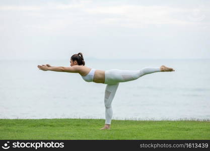 Healthy Asian woman practicing yoga Balancing stick Pose stretching exercises muscle for warm up on the beach in thailand