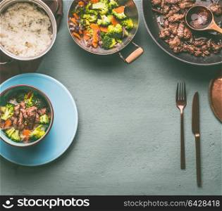 Healthy balanced nutrition food with beef meat, steamed vegetables and rice on table background with plate and cutlery, top view, frame with copy space