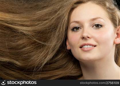 Healthy beautiful long hair closeup in motion created by wind. Portrait on black background