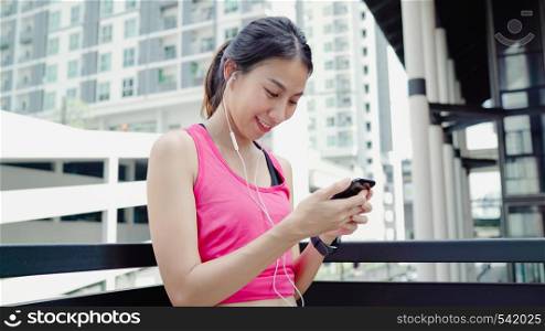 Healthy beautiful young Asian Athlete woman using smartphone for listen to music while running in urban city. Lifestyle women exercise in the city concept.