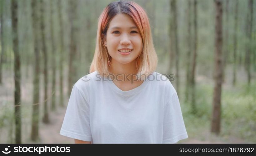 Healthy beautiful young Asian runner woman feeling happy smiling and looking to camera after running on forest trail. Lifestyle fit and active women exercise in the forest concept.