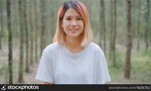 Healthy beautiful young Asian runner woman feeling happy smiling and looking to camera after running on forest trail. Lifestyle fit and active women exercise in the forest concept.