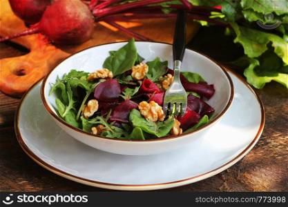 Healthy Beet Salad with fresh sweet baby spinach, arugula, nuts on wooden background .. Healthy Beet Salad with fresh sweet baby spinach, arugula, nuts on wooden background