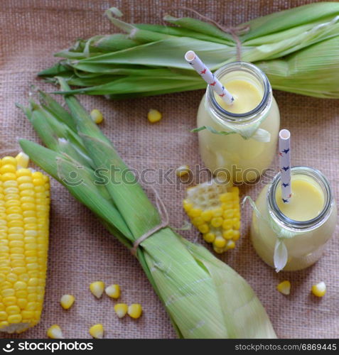 Healthy beverage for breakfast from sweetcorn, corn milk jar in yellow, rich vitamin, tasty, nutrition from maize, fresh milk bottle on wooden background