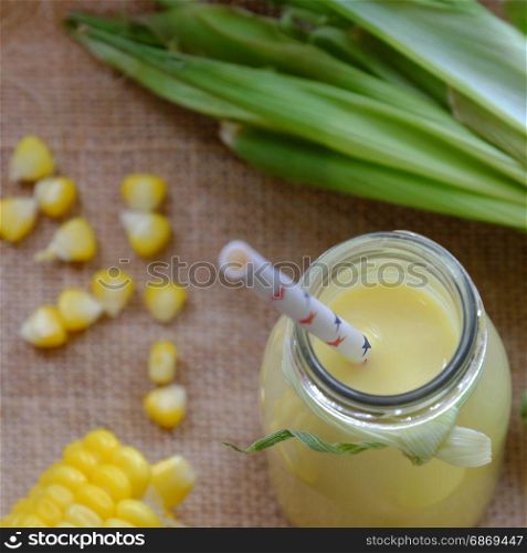 Healthy beverage for breakfast from sweetcorn, corn milk jar in yellow, rich vitamin, tasty, nutrition from maize, fresh milk bottle on wooden background