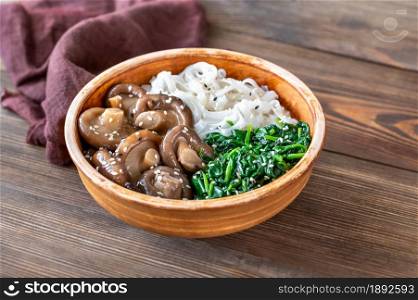 Healthy bowl with rice noodles, marinated shiitake and steamed spinach