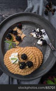 Healthy breakfast. Belgian waffles with fresh wild blackberries and cream cheese in dark background.