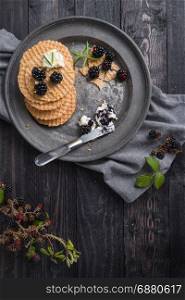 Healthy breakfast. Belgian waffles with fresh wild blackberries and cream cheese in dark background.