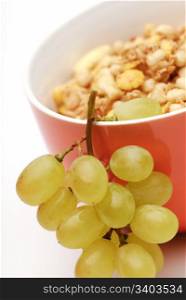 Healthy breakfast, bunch of grapes in a bowl of muesli. White background, selective focus, vertical crop.