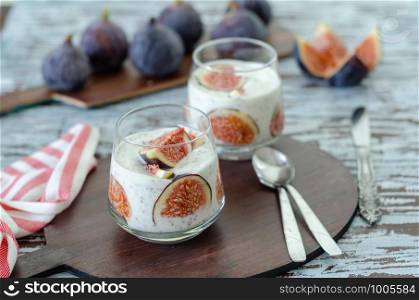 Healthy breakfast from natural ingredients .Homemade yogurt, slice of the fig, chia seeds and yogurt in glasses on the wooden background, close up.