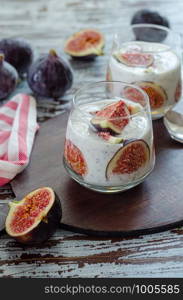 Healthy breakfast from natural ingredients .Homemade yogurt, slice of the fig, chia seeds and yogurt in glasses on the wooden background, close up.