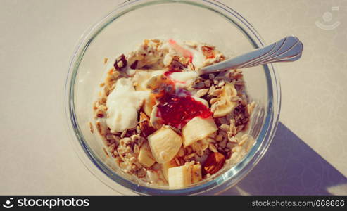 Healthy breakfast oatmeal granola with yogurt, banana fruits and sunflower seeds in bowl, sunny morning. Healthy breakfast oatmeal with fruits