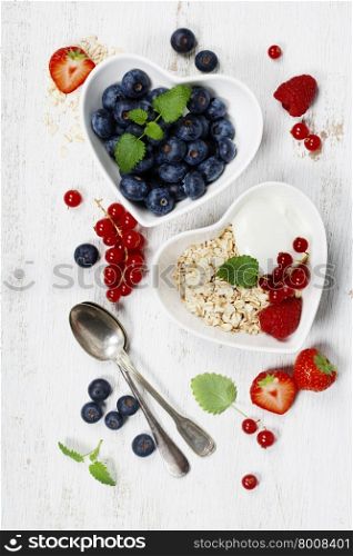 Healthy breakfast of muesli, berries with yogurt and seeds on white background - Healthy food, Diet, Detox, Clean Eating or Vegetarian concept.