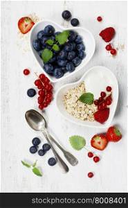 Healthy breakfast of muesli, berries with yogurt and seeds on white background - Healthy food, Diet, Detox, Clean Eating or Vegetarian concept.