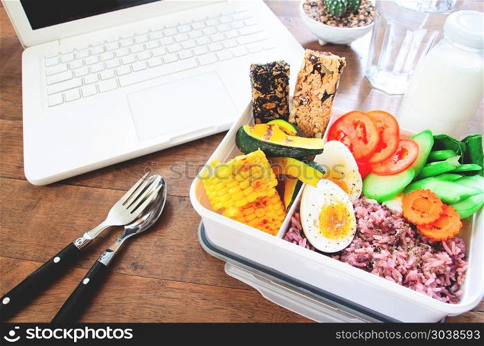 Healthy breakfast or lunch box with rice berry, boiled eggs, car. Healthy breakfast or lunch box with rice berry, boiled eggs, carrot, tomatoes, corns, pumpkin and cereal bars on workspace desk, Food and Health