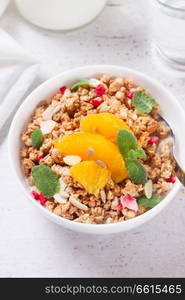 Healthy breakfast - plate of granola with orange slices, mint leaves and seeds close up. Healthy breakfast with granola