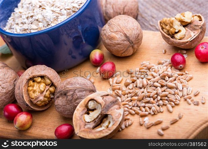 healthy breakfast - wheat, oatmeal, cranberries, nuts, grapes on a wooden table