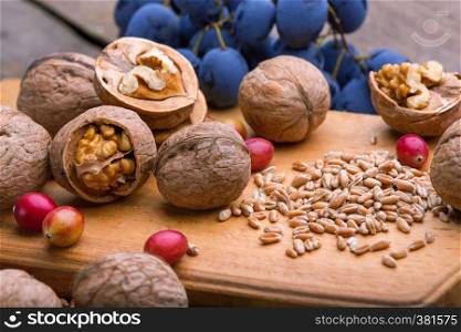 healthy breakfast - wheat, oatmeal, cranberries, nuts, grapes on a wooden table