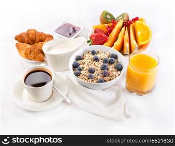healthy breakfast with bowl of muesli, coffee, croissants, juice and fruits