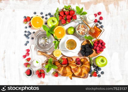 Healthy breakfast with coffee, croissants, muesli, milk, fresh berries, fruits. Top view