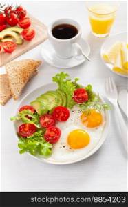 healthy breakfast with fried eggs, avocado, tomato, toasts and coffee
