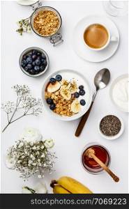 Healthy breakfast with granola, yogurt, coffee, fruits and chia seeds, flat lay, top view, white background, copy space