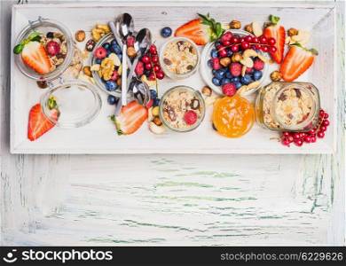 Healthy breakfast with muesli and summer berries and nuts. Fresh granola, muesli and berries in glass jars on light shabby chic wooden background, top view, place for text