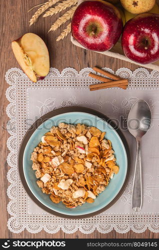 Healthy breakfast with muesli, red apple and cinnamon on rustic wooden table. Top view with copy space.