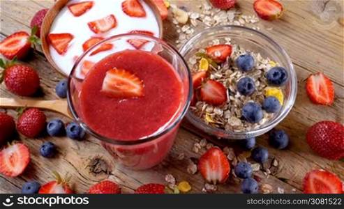Healthy breakfast with strawberry smoothie, yogurt and cereals. Handheld movement.