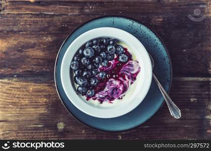 healthy breakfast yoghurt with blueberries and sauce on wood