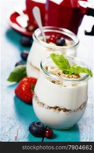 Healthy breakfast - yogurt with muesli and berries - health and diet concept. Blue background