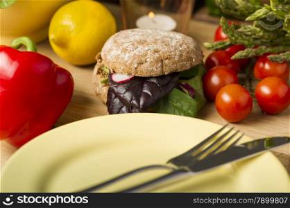 Healthy Burger Beside Fresh Ingredients and Plate. Close Healthy Burger with Leafy Veggies Beside Fresh Ingredients and Plate with Fork and Knife