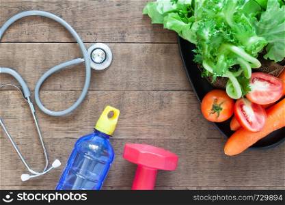Healthy concept, stethoscopes and fresh vegetables on wooden background.