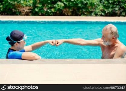 Healthy couple elder happy playing together at swimming pool, enjoy fun summer vacation life after Covid-19.