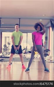 healthy couple workout with weights lifting dumbbels at crossfit gym african american woman with afro hairstyle. couple workout with weights at crossfit gym
