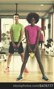 healthy couple workout with weights lifting dumbbels at crossfit gym african american woman with afro hairstyle. couple workout with weights at crossfit gym