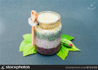 Healthy dessert and proper nutrition concept. Chia pudding in glass jar with wooden spoon. Chia seeds. Superfood. Selective focus. Milk dessert