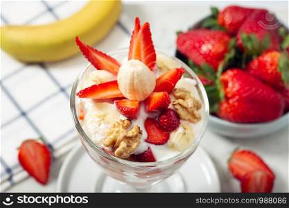 Healthy dessert in glass with strawberries, banana, yogurt and walnut. Healthy food concept