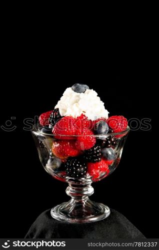 Healthy dessert of mixed berries and whipped cream. Black background