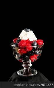 Healthy dessert of mixed berries and whipped cream. Black background