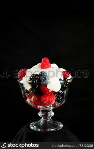Healthy dessert of mixed berries topped with vanilla Greek yogurt. Black background with room for text.