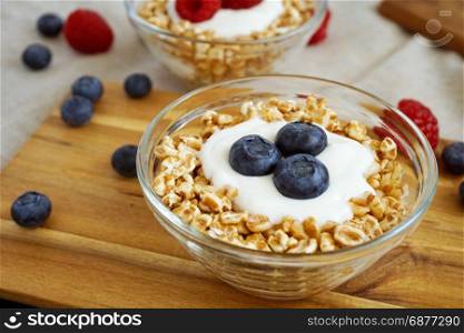 Healthy diet breakfast with a bowl of yogurt, spelt flakes and mixed fresh berries fruit.