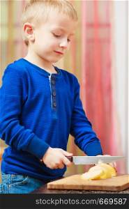 Healthy diet for children, youngsters cooking concept. Little boy peeling apples with knife and eating. Little boy peeling apples with knife and eating