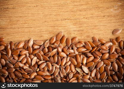 Healthy diet organic nutrition. Brown raw flax seeds linseed border frame on wooden table background