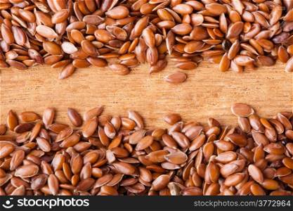 Healthy diet organic nutrition. Brown raw flax seeds linseed border frame on wooden table background